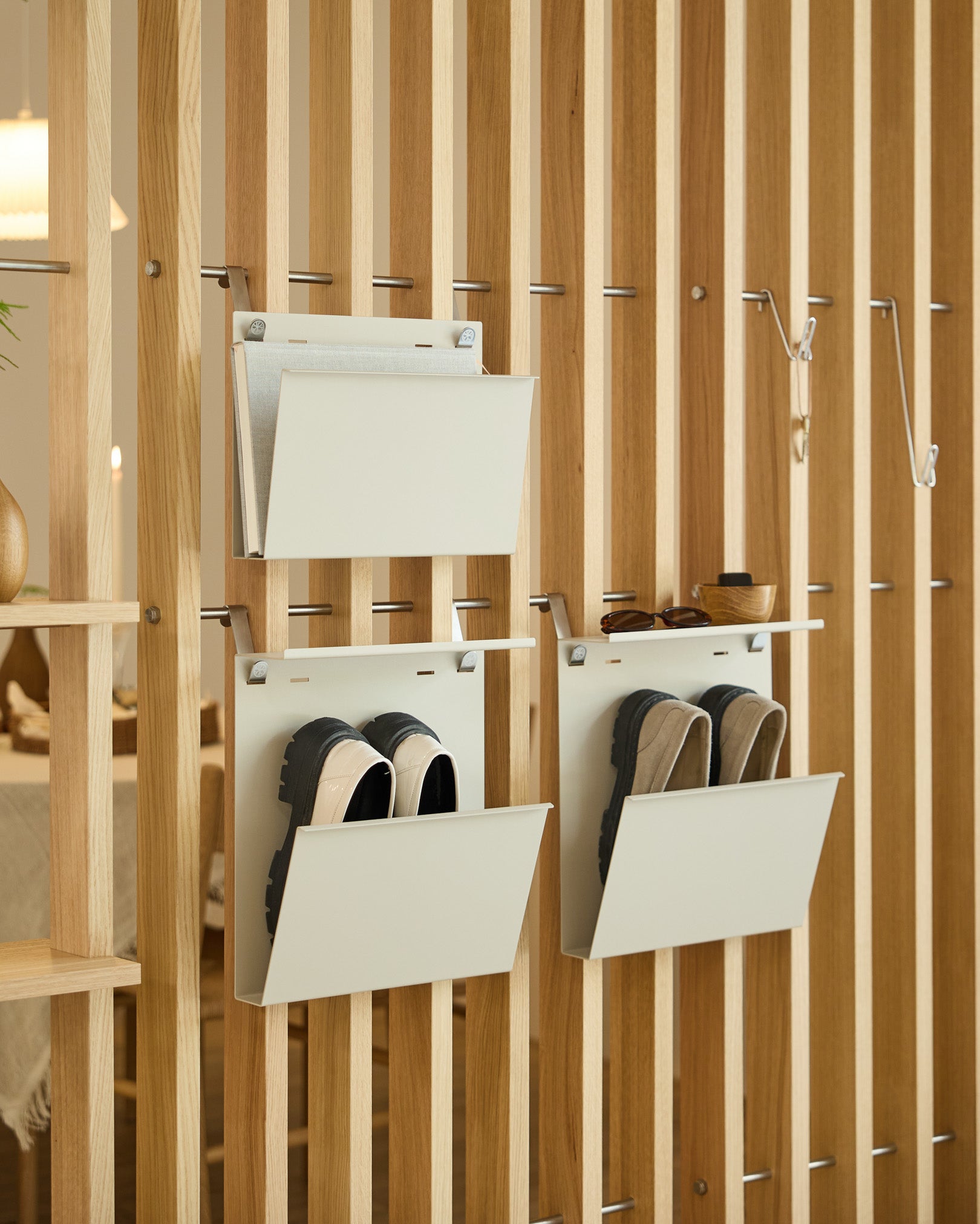 Nell Magazine Storage fra WoodUpp i beige er fastgjort til en lodret rumdeler og giver organiseret opbevaring af magasiner og småting.